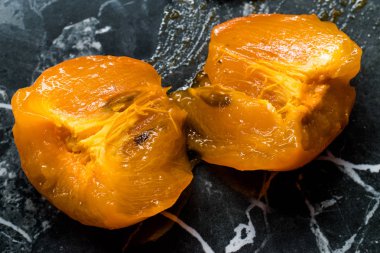 Yarı yarıya Çiğ Organik Sulu Meyve Suyu Kara Granit Yüzeyde Yemeye Hazır. 