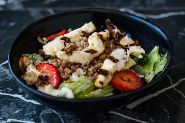 Grilled Halloumi Cheese Salad with Strawberry Slices and Buckwheat / Hellim in Black Bowl on Dark Granite Surface. Organic Fresh Food. — Stock Photo, Image