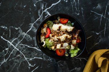 Izgara Halloumi Peynir Salatası ve Çilek Dilimleri ve Karabuğday / Hellim in Black Bowl on Dark Granite Surface. Organik Taze Yiyecek.
