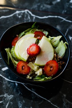 Çilekli Elma Salatası, Karabuğday ve Yeşil Yapraklar Kara Granit yüzeyde Kara Kasede.