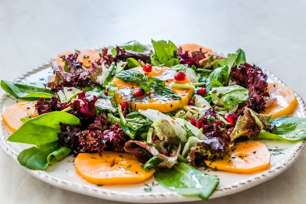 Persimmon Gyümölcssaláta gránátalmával, Lollo Rosso salátával, Rocket Arugulával vagy Rucolával és mentalevéllel. Bioélelmiszerek. — Stock Fotó