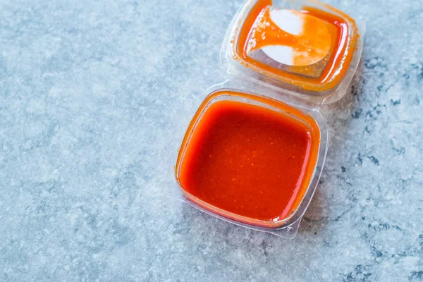 Scharfe rote Sriracha-Sauce in Plastikbox / Verpackung oder Behälter für Fast Food fertig zum Essen. traditionelle Soße. — Stockfoto