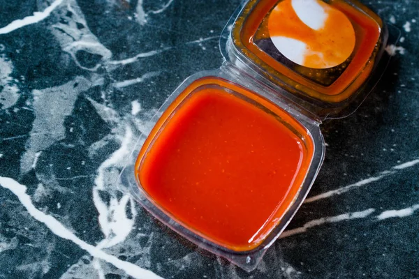 Scharfe rote Sriracha-Sauce in Plastikbox / Verpackung oder Behälter für Fast Food fertig zum Essen. traditionelle Soße. — Stockfoto
