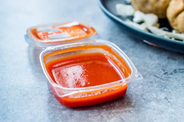 Scharfe rote Sriracha-Sauce in Plastikbox / Verpackung oder Behälter für Fast Food fertig zum Essen. traditionelle Soße. — Stockfoto