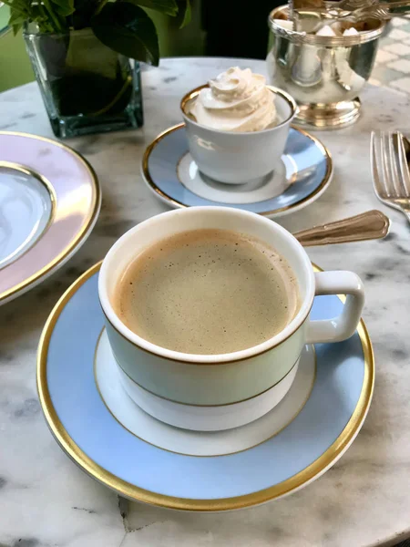 Taza de café de porcelana con Macarrón / Macaron en Cafetería con crema servida sobre mesa de mármol. Listo para comer . — Foto de Stock