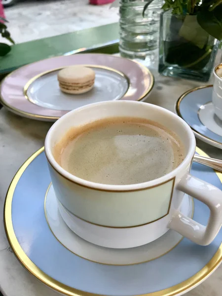 Taza de café de porcelana con Macarrón / Macaron en Cafetería con crema servida sobre mesa de mármol. Listo para comer . — Foto de Stock