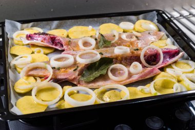 Fırında pişirilmeye hazır fırında patates ve soğanla ızgarada pişirilmiş çiğ deniz levreği filetosu. Organik Gıda.