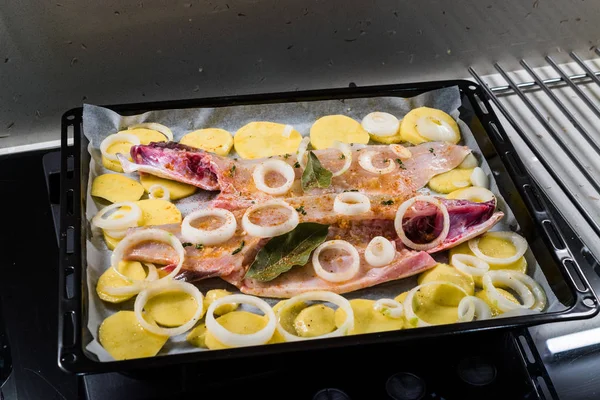 Filete crudo de lubina a la parrilla con patatas y cebollas en bandeja para hornear listo para hornear en horno. Alimentos ecológicos . —  Fotos de Stock