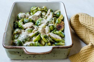 Porselen kâse üzerinde sütlü krema sosuyla pişirilmiş Brüksel lahanası..