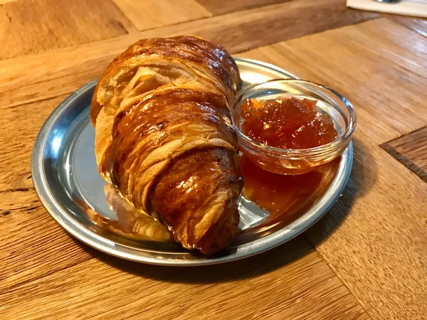 Croissant z dżemem / marmoladą w srebrnej tablicy na drewnianym stole w Cafe Shop na śniadanie. Gotowość do serwowania i jedzenia. — Zdjęcie stockowe