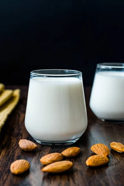 Amandelmelk in glazen bekers met amandelen en doek. — Stockfoto