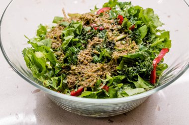 Bitki soslu ev yapımı salata ve cam kasede iki kaşıkla karıştırılmış kırmızı biber dilimleri. Organik Taze Yiyecek.