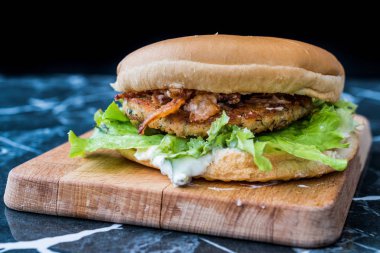 Ev yapımı Tartar soslu Somon Burger, Mermer Tahtada Soğan ve Marul. Yemeye hazır..