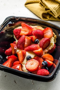 Çilekli tart dilimini plastik kutuda ya da pakette çilekle birlikte götür. Teslimat ve yemek için hazır..