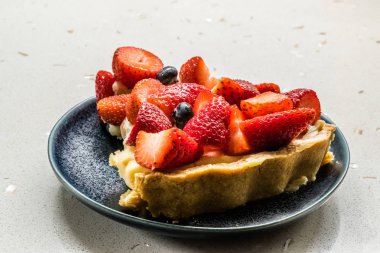 Çilekli tart dilimi ve içi çilek dolu tabaklar..