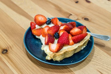 Çilekli tart dilimi ve içi çilek dolu tabaklar..