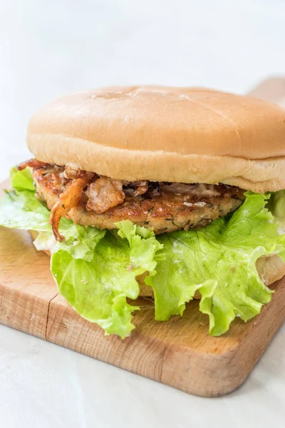 Homemade Salmon Burger with Tartar Sauce, Onion and Lettuce on Marble Board. Ready to Eat.