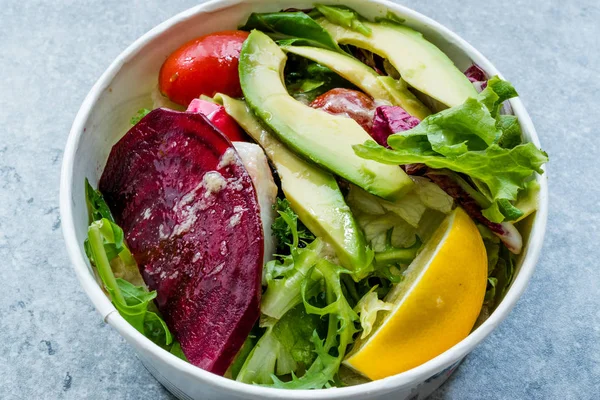 Healthy Fast Food Take Away Salad with Avocado, Beet Slice, Lettuce, Cherry Tomatoes and Sauce in Plastic Box / Package or Container. Organic Fresh Food.