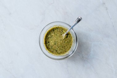 Ev yapımı yeşil bitkisel salata sosu, içinde bitki kökleri ve kaşıkla birlikte cam kasede. Organik Ev Yapımı Yemekler.