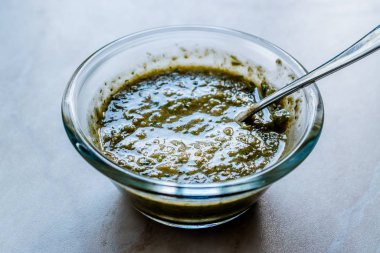 Ev yapımı yeşil bitkisel salata sosu, içinde bitki kökleri ve kaşıkla birlikte cam kasede. Organik Ev Yapımı Yemekler.