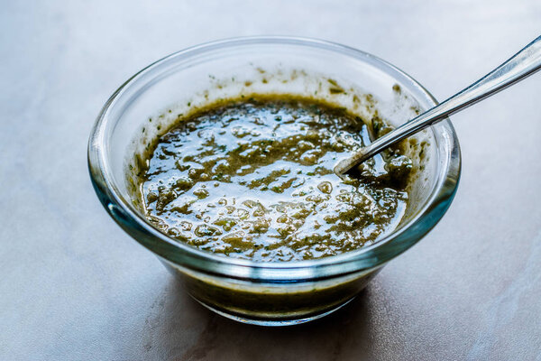 Homemade Green Herbal Salad Sauce with Plant Roots in Glass Bowl with Spoon. Organic Homemade Food.