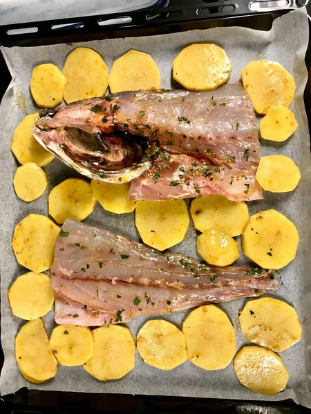 Filetes de peixe cru Sciaena Umbra com fatias de batata na folha de papel da bandeja de cozimento no forno / pronto para assar. Produtos do mar orgânicos . — Fotografia de Stock