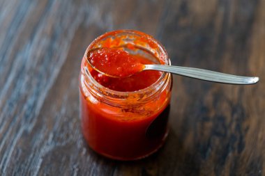 Sanatçı Peyniri için kırmızı acı biber sosu. Sirke ve şekerle yapılmış, kaşıkla cam kasede..