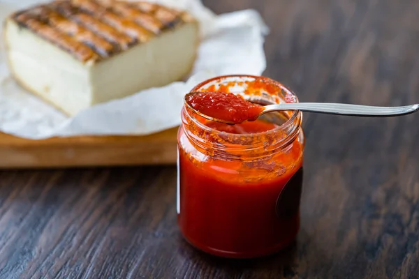 Molho de pimenta vermelha quente para queijo artesanal feito com vinagre e açúcar em tigela de vidro com colher . — Fotografia de Stock