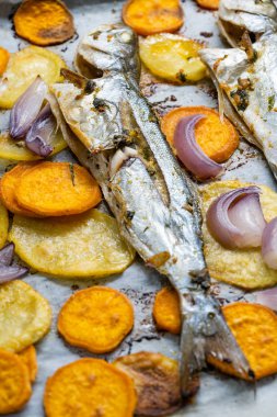 Fırın tepsisinde tatlı patatesli fırınlanmış balık mavisi balık ve kağıt levha / Lufer. Deniz ürünleri..