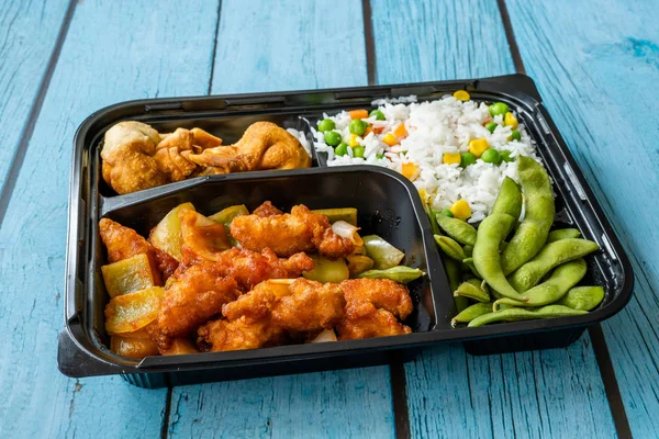 Take Away Japanese Food Bento Box Menu Set with Chicken, Fried Dumplings, Edamame and Rice with Vegetables in Plastic Box Package / Container. Traditional Healthy Fast Food.