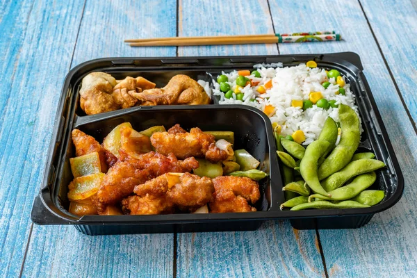 Take Away Japanese Food Bento Box Menu Set with Chicken, Fried Dumplings, Edamame and Rice with Vegetables in Plastic Box Package / Container. Traditional Healthy Fast Food.