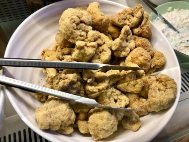 Çökmüş ve Kızarmış Karnabahar. Kızarmış sebzeler Metal Çelik Mutfak Tong Organik Gıda ile servis etmeye hazır..