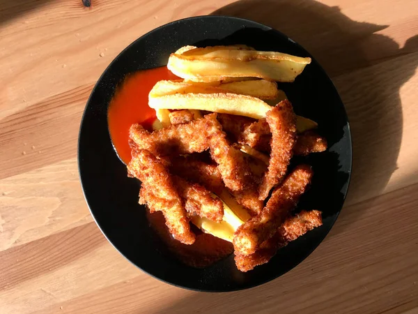 Fish and Chips aus paniertem und gebratenem Seebarsch auf schwarzem Teller. Fast Food. — Stockfoto
