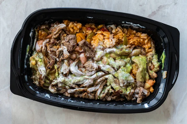 将墨西哥食品卡恩 · 阿萨达牛排片、瓜卡莫尔酱、平托豆和大米装在塑料容器/包装盒中带走。 传统食品. — 图库照片