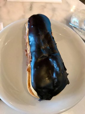 Traditional Big French Eclair with Chocolate served with Plate at Patisserie. Ready to Eat.