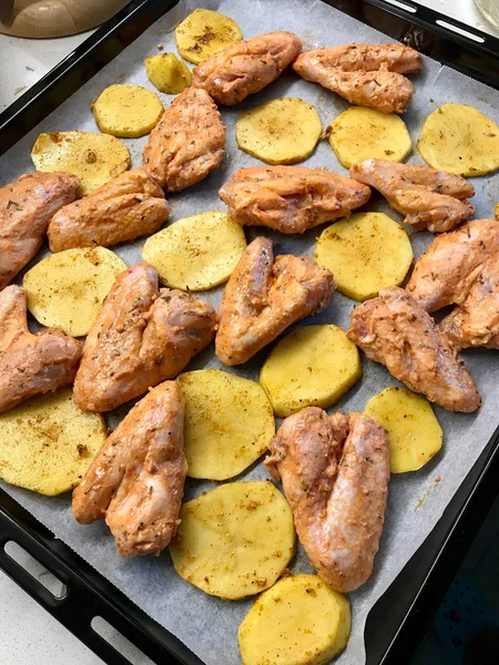Homemade Marinated Raw Chicken Wings with Sliced Potato Slices and Sauce on Baking Tray with Oven Sheet Paper Ready to Bake. Organic Food. — 스톡 사진