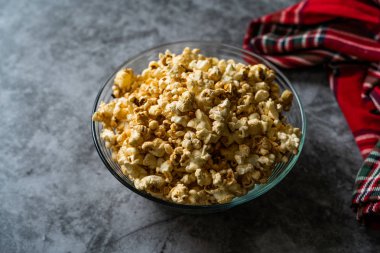 Gri Yüzeyde Cam Kasede Karamelli Patlamış Mısır.