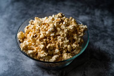 Gri Yüzeyde Cam Kasede Karamelli Patlamış Mısır.