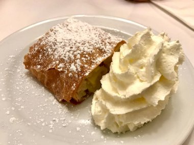Orijinal Geleneksel Apple Strudel, Viyana, Avusturya 'da Apfelstrudel. Restoran ortamında beyaz bir tabakta servis edilmiş. Vanilyalı dondurma, pudra şekeri ve nane yaprağı. Yemeye hazır..