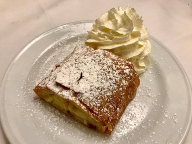 Orijinal Geleneksel Apple Strudel, Viyana, Avusturya 'da Apfelstrudel. Restoran ortamında beyaz bir tabakta servis edilmiş. Vanilyalı dondurma, pudra şekeri ve nane yaprağı. Yemeye hazır..