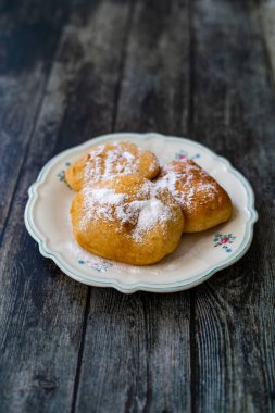 Mandazi is a slightly sweet East African Street Food; spicy, airy yeast doughnut dough made with coconut milk, flavored with cardamom and grated fresh coconut. Traditional Dish.