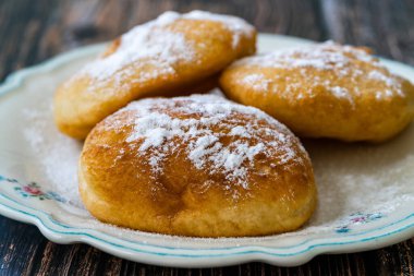 Mandazi is a slightly sweet East African Street Food; spicy, airy yeast doughnut dough made with coconut milk, flavored with cardamom and grated fresh coconut. Traditional Dish.