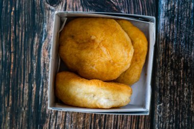Take Away Mandazi is a slightly sweet East African Street Food; spicy, airy yeast doughnut dough made with coconut milk, flavored with cardamom and grated fresh coconut in Plastic Box Container. Ready to Eat.
