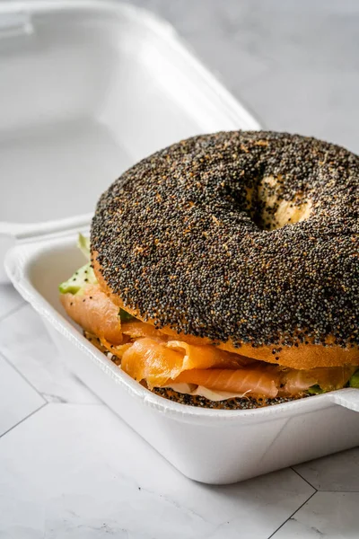 Take Away Salmon Bagel Sandwich with Lox Cream Cheese and Poppy Seeds in Plastic Container Box Package. Organic Healthy Fast Food.