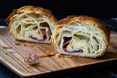 Taze pişmiş yarım dilim kruvasan, domuz pastırması ve Çedar çok yumuşak. Yemeye hazır..