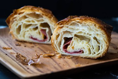 Taze pişmiş yarım dilim kruvasan, domuz pastırması ve Çedar çok yumuşak. Yemeye hazır..