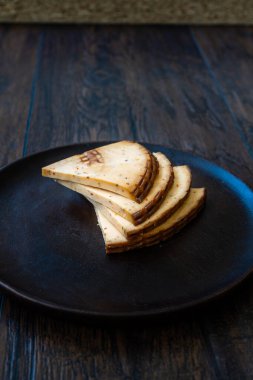 Baharatlı Çerkez Üçgeni Koyu Ahşap Tabakta Füme Peynir Dilimleri ve Baharatlar. Yemeye hazır..