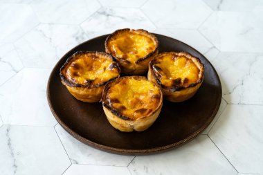 Pasteis de Nata veya Belem Tart. Tahta tabakta yumurta, tarçın, şeker ve un ile yapılmış Portekiz kreması. Geleneksel Tatlı.