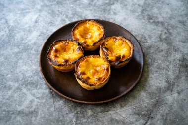 Pasteis de Nata veya Belem Tart. Tahta tabakta yumurta, tarçın, şeker ve un ile yapılmış Portekiz kreması. Geleneksel Tatlı.