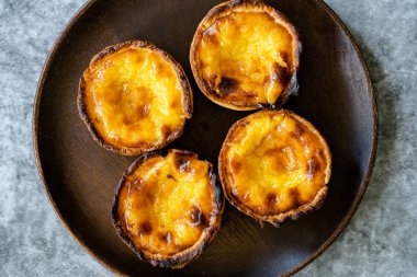 Pasteis de Nata veya Belem Tart. Tahta tabakta yumurta, tarçın, şeker ve un ile yapılmış Portekiz kreması. Geleneksel Tatlı.